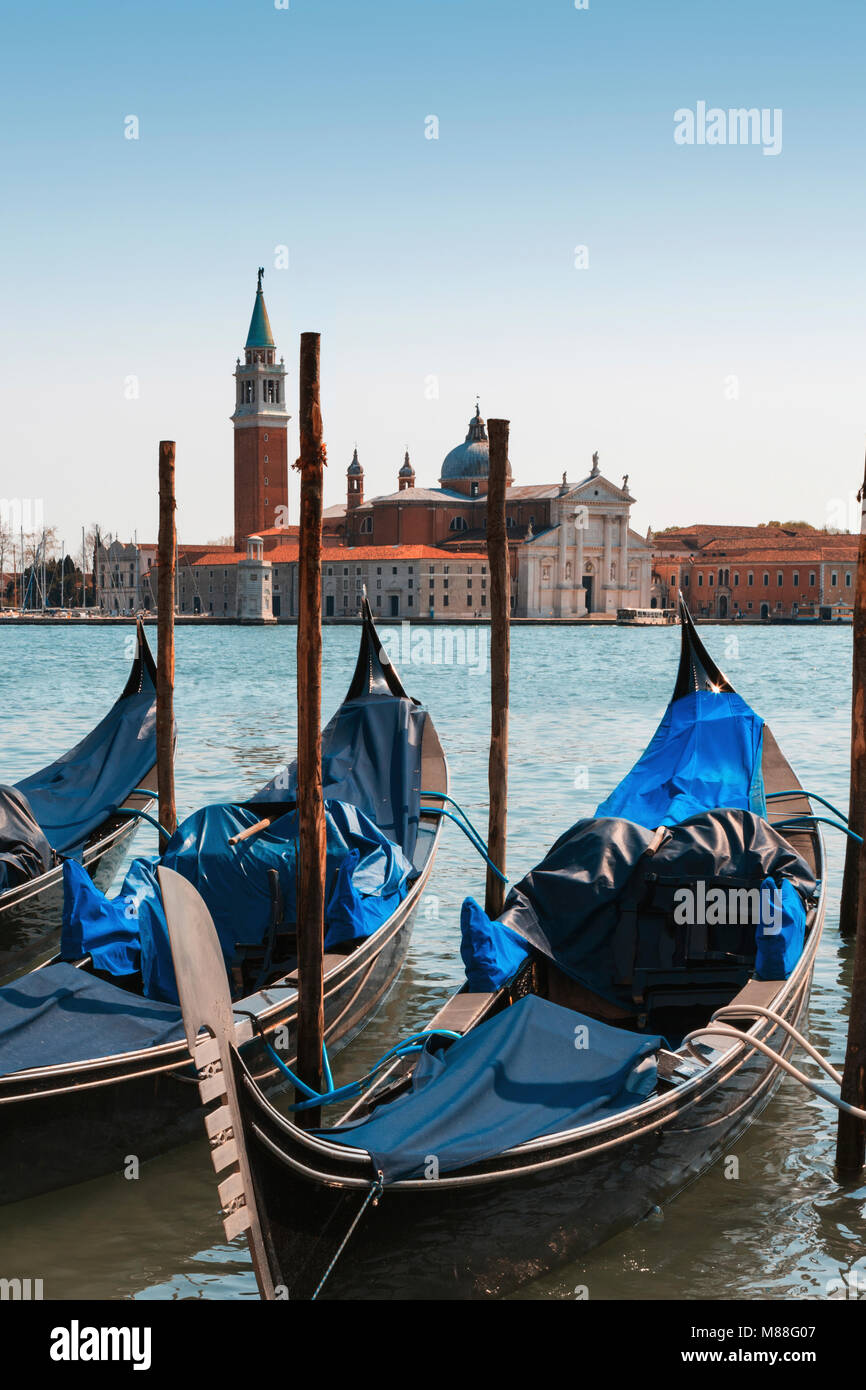 Drei schwarzen gondeln zu Beiträge gebunden am Ufer an der Piazzetta di San Marco in Venedig, flankiert von hohen camponile Turm der Renaissance und der Katholischen Kirche Stockfoto