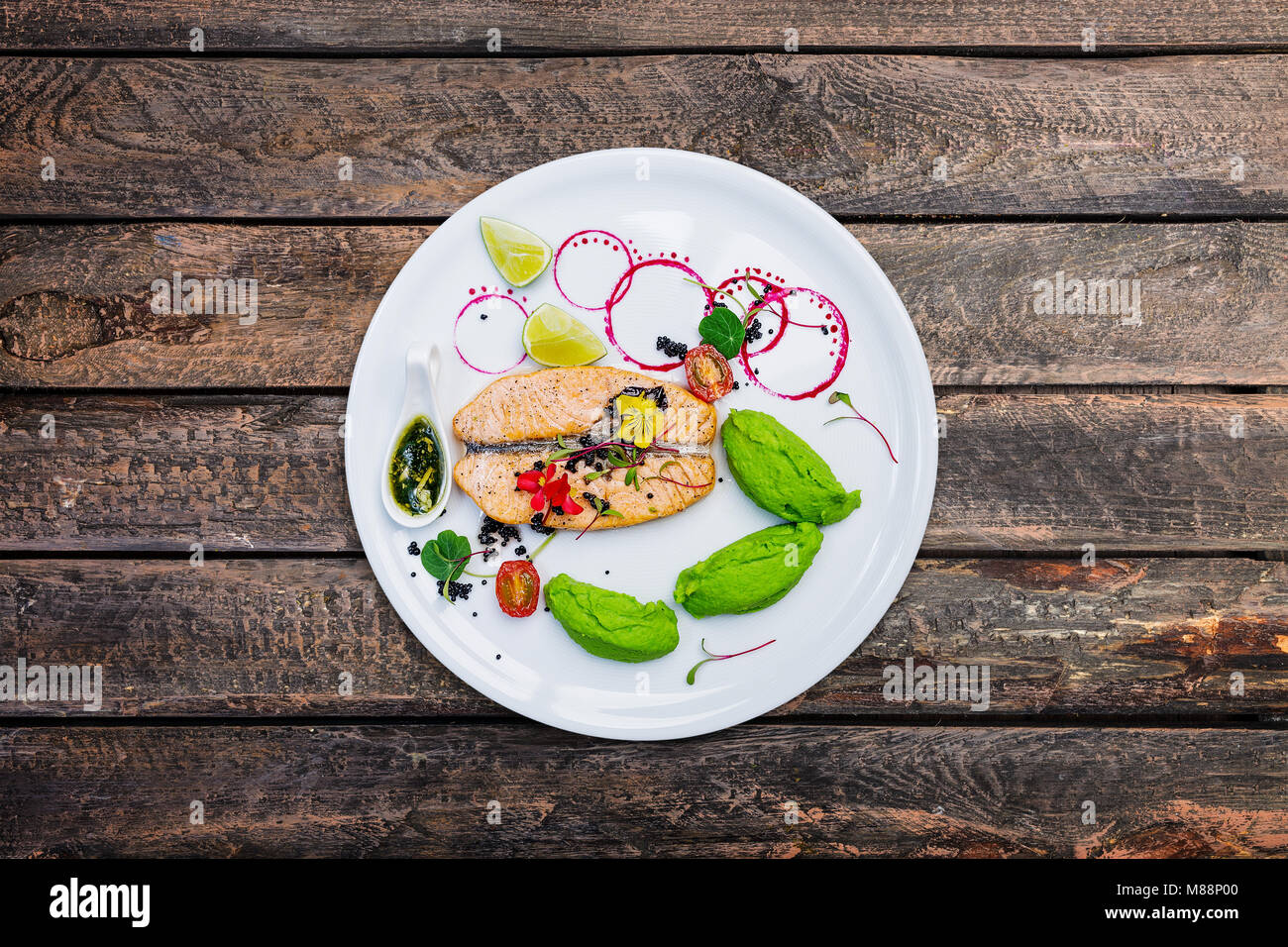 Gegrillter Lachs mit Erbsenpüree auf einem weißen Teller. Stockfoto