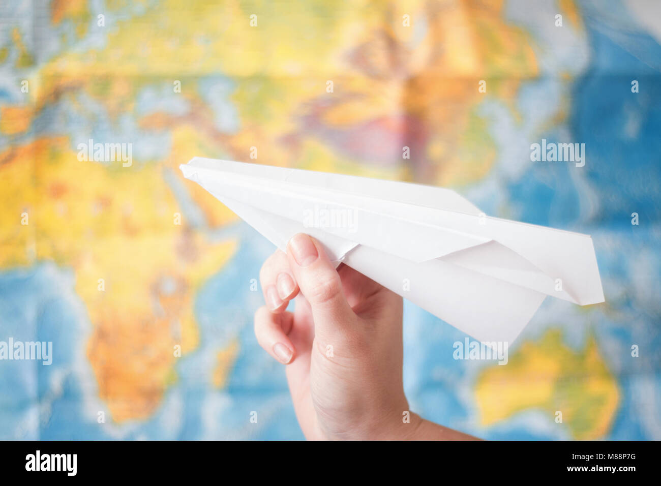 Papierflieger in der Hand auf Weltkarte Hintergrund. Travel Concept Stockfoto