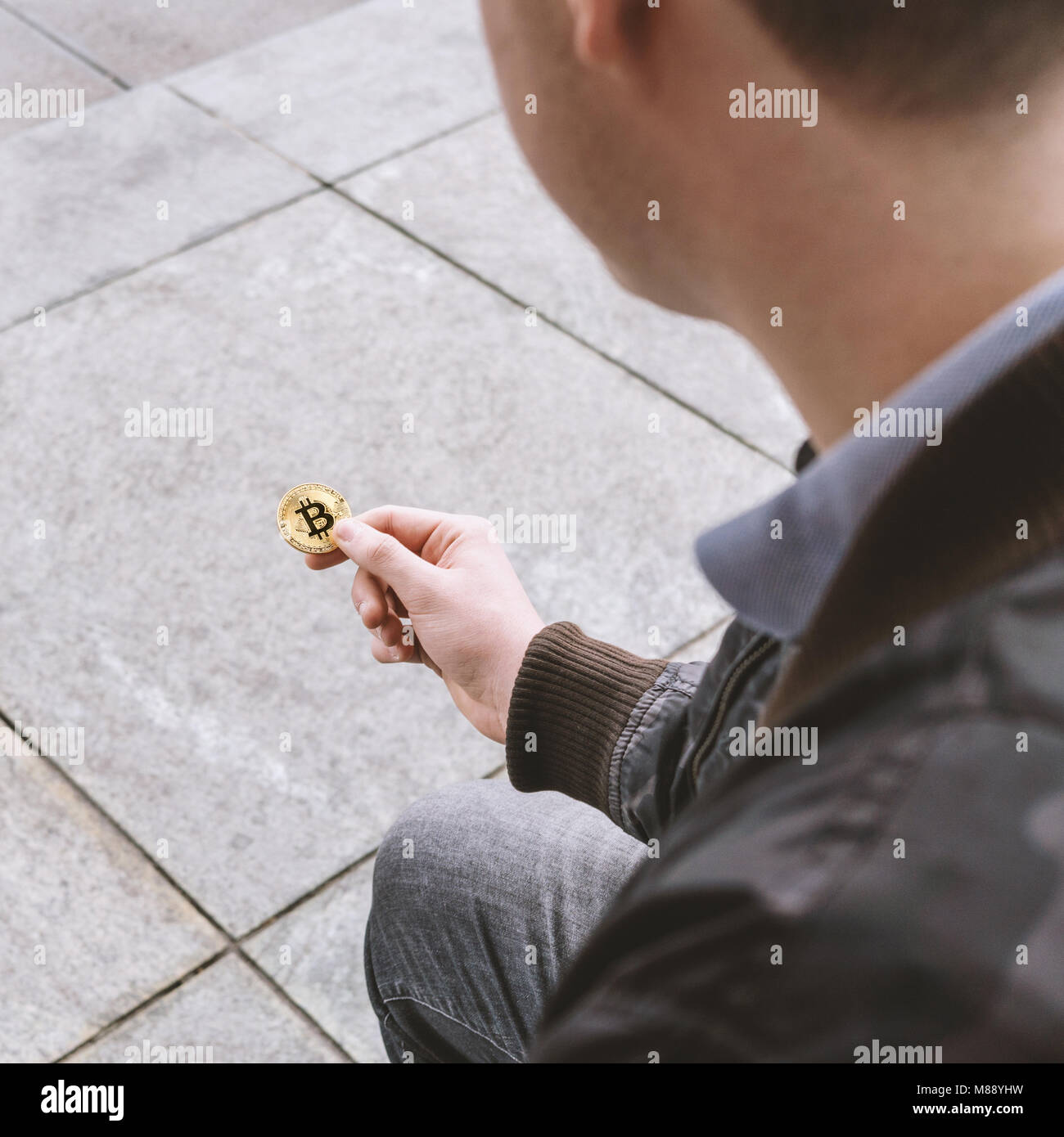 Junger Mann mit bitcoin Münze in der Hand Stockfoto