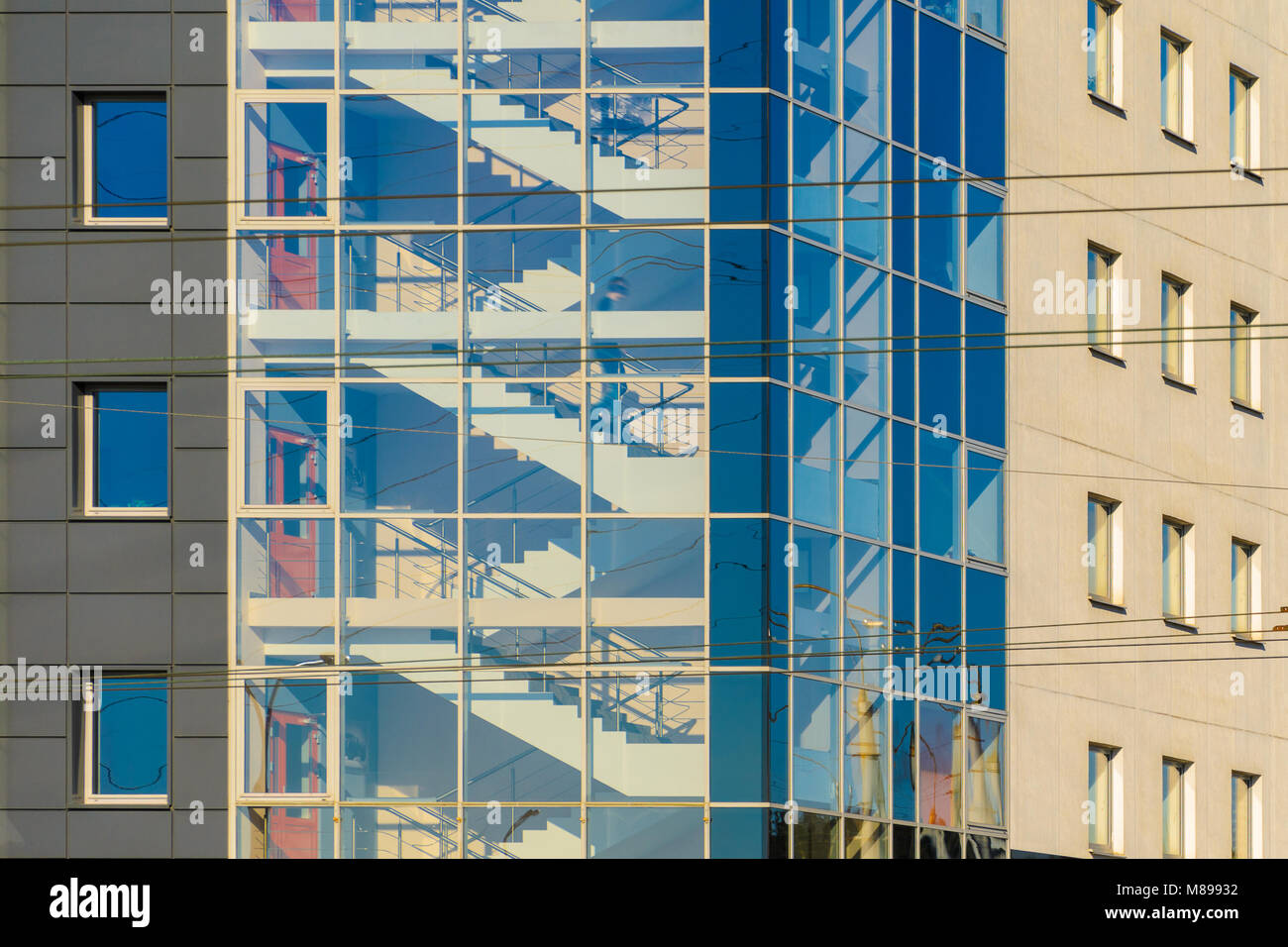 Abbildung eines Mannes im Treppenhaus eines Bürogebäudes hinter einer Glasfassade. Treppe mit Glasfassade in einem Büro Gebäude Architektur Backgroun Stockfoto