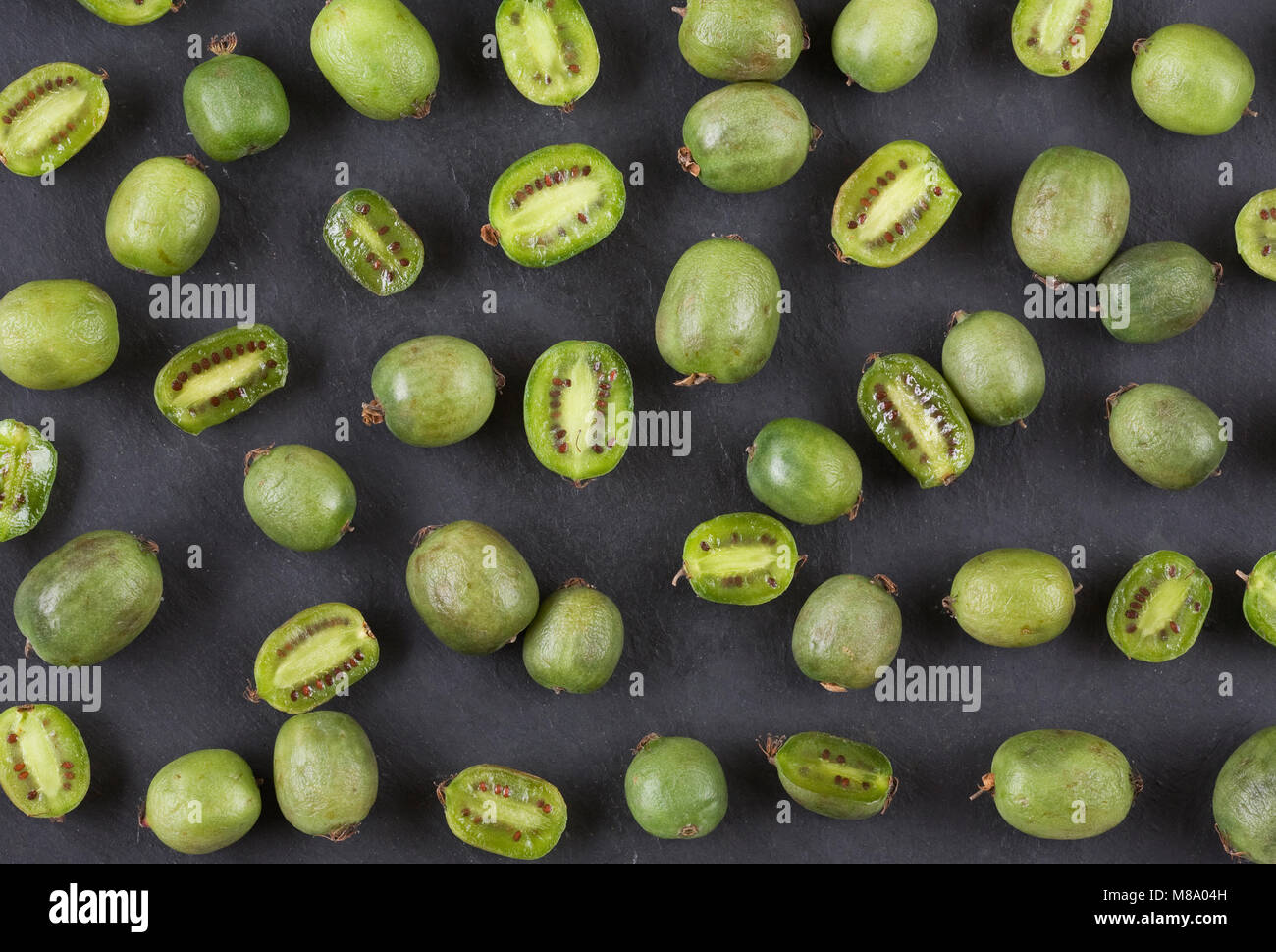 Actinidia arguta. Kiwi Beeren auf einem Schiefer Hintergrund. Stockfoto