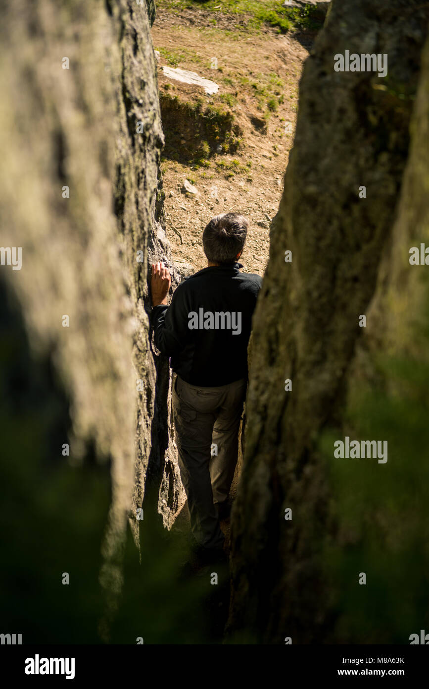 Jungen Erwachsenen aktiven Mann Wanderung durch die schmalen Pfad zwischen Felswände in sonnigen Sommertag auf mountian Outdoor. Stockfoto