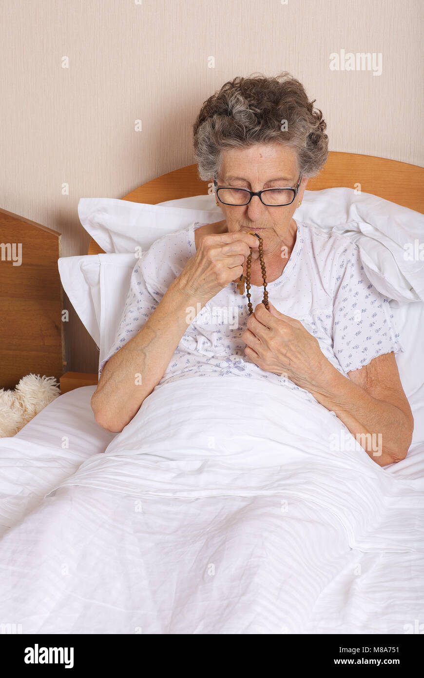 Ältere Frau zwischen 70 und 80 Jahre alt ist das Beten in Ihrem Bett Stockfoto