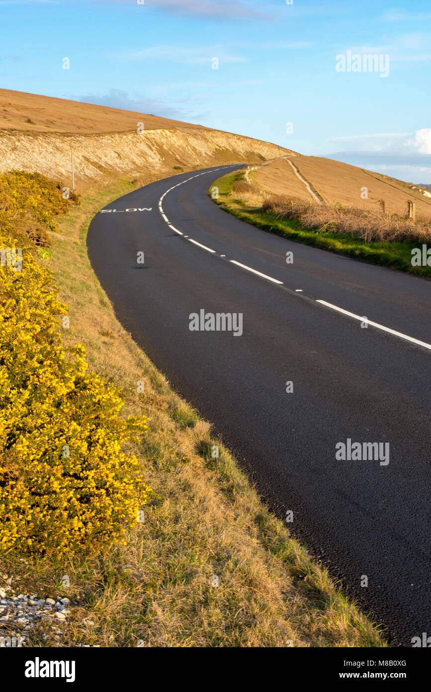 Eine Straße oder Autobahn in den Hügeln über dem Horizont verschwinden mit einem blauen Himmel. Fahr- und motorisch endlos ewigen Straßen und Strecken, die durch die Hügel. Stockfoto