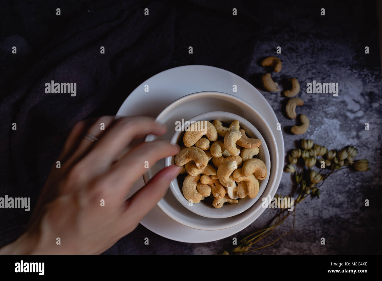 Cashewkerne in weißen Schalen. Der dunkle Hintergrund. Stockfoto