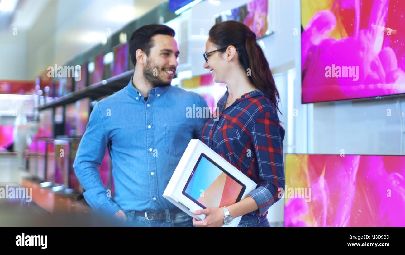 Junges Paar macht Shopping in der Unterhaltungselektronik, Sie haben bereits Gewählt neuesten Tablet Computer für sich. Store ist hell, Moden Stockfoto