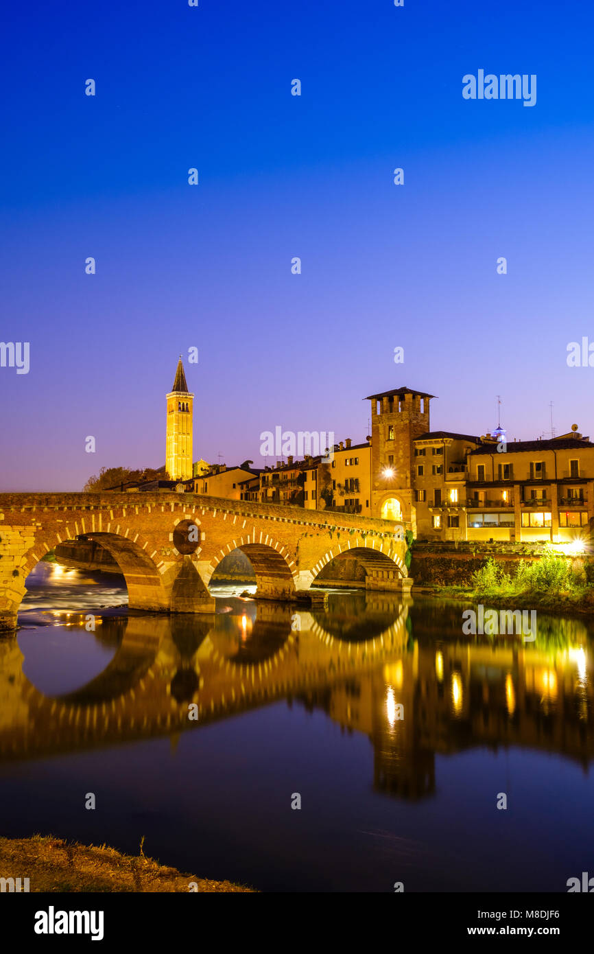 Der Ponte Pietra über die Etsch in der Nacht. Das Campanile di Santa Anastasia Verona ist im Hintergrund sichtbar. Stockfoto