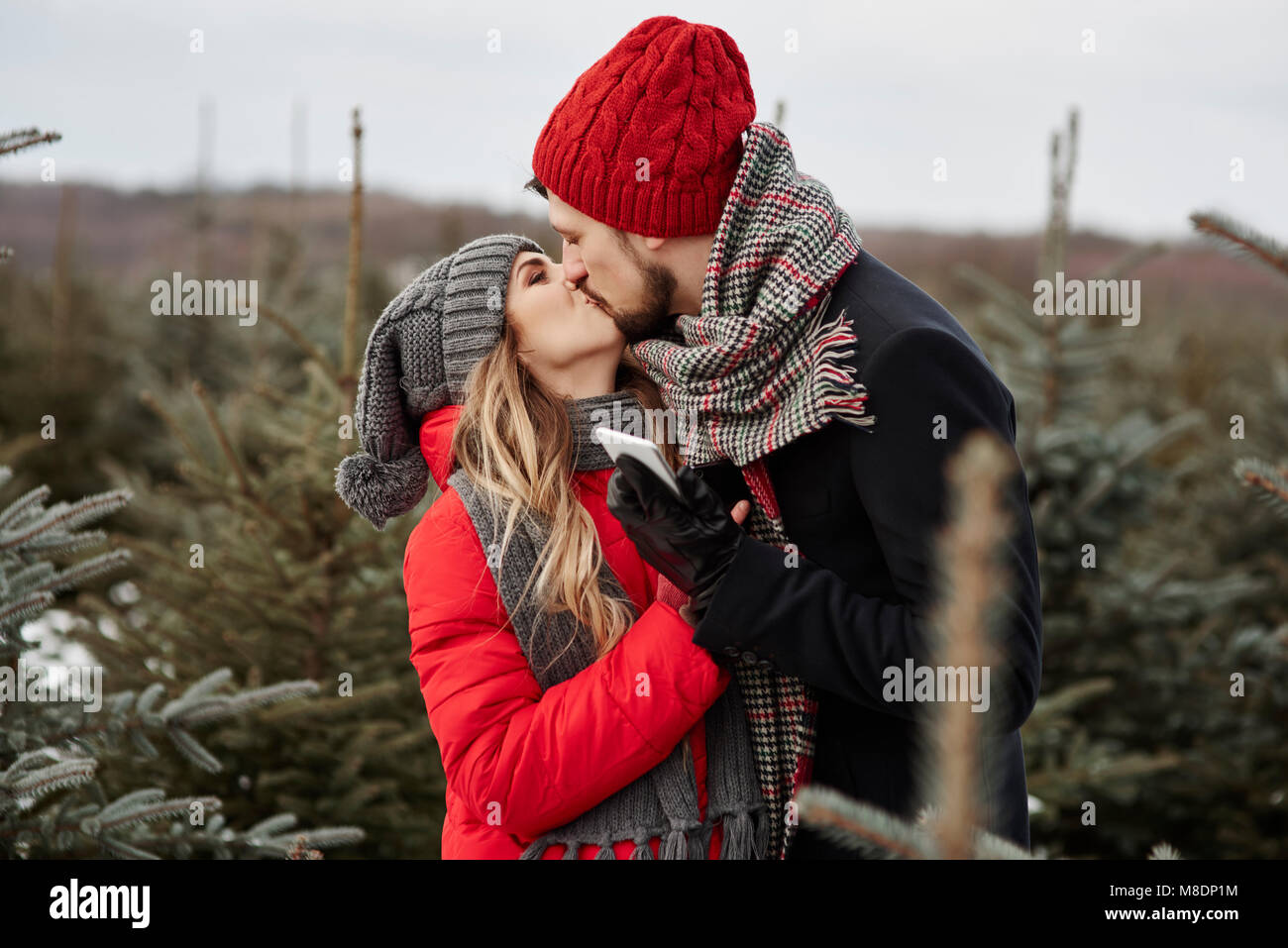 Romantische junge Paar küssen beim Einkauf für Weihnachtsbaum aus Wald Stockfoto