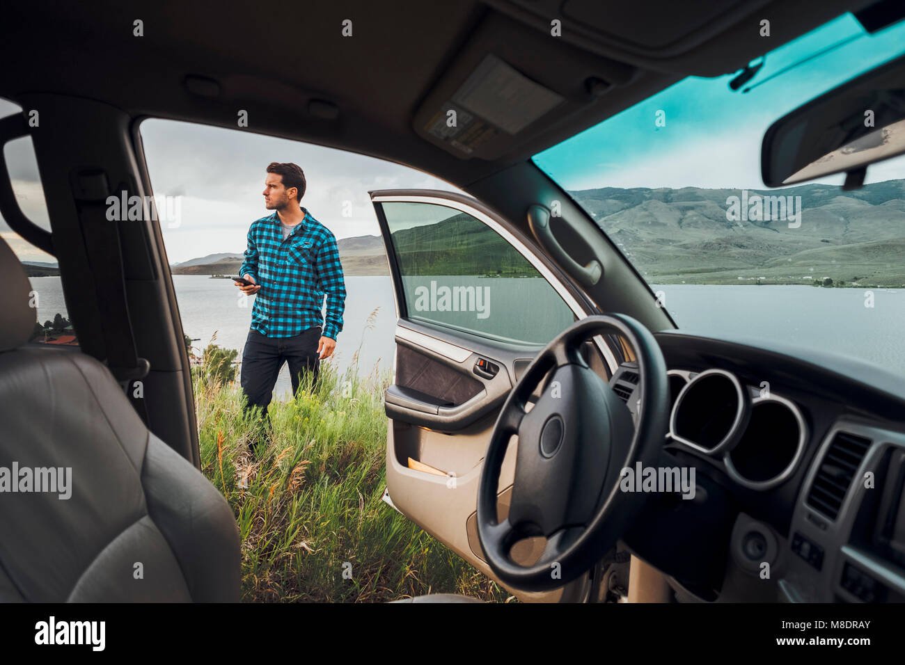 Mitte der erwachsene Mann stand neben Dillon Reservoir, Smartphone, Blick durch die geparkten Auto, Silverthorne, Colorado, USA Stockfoto