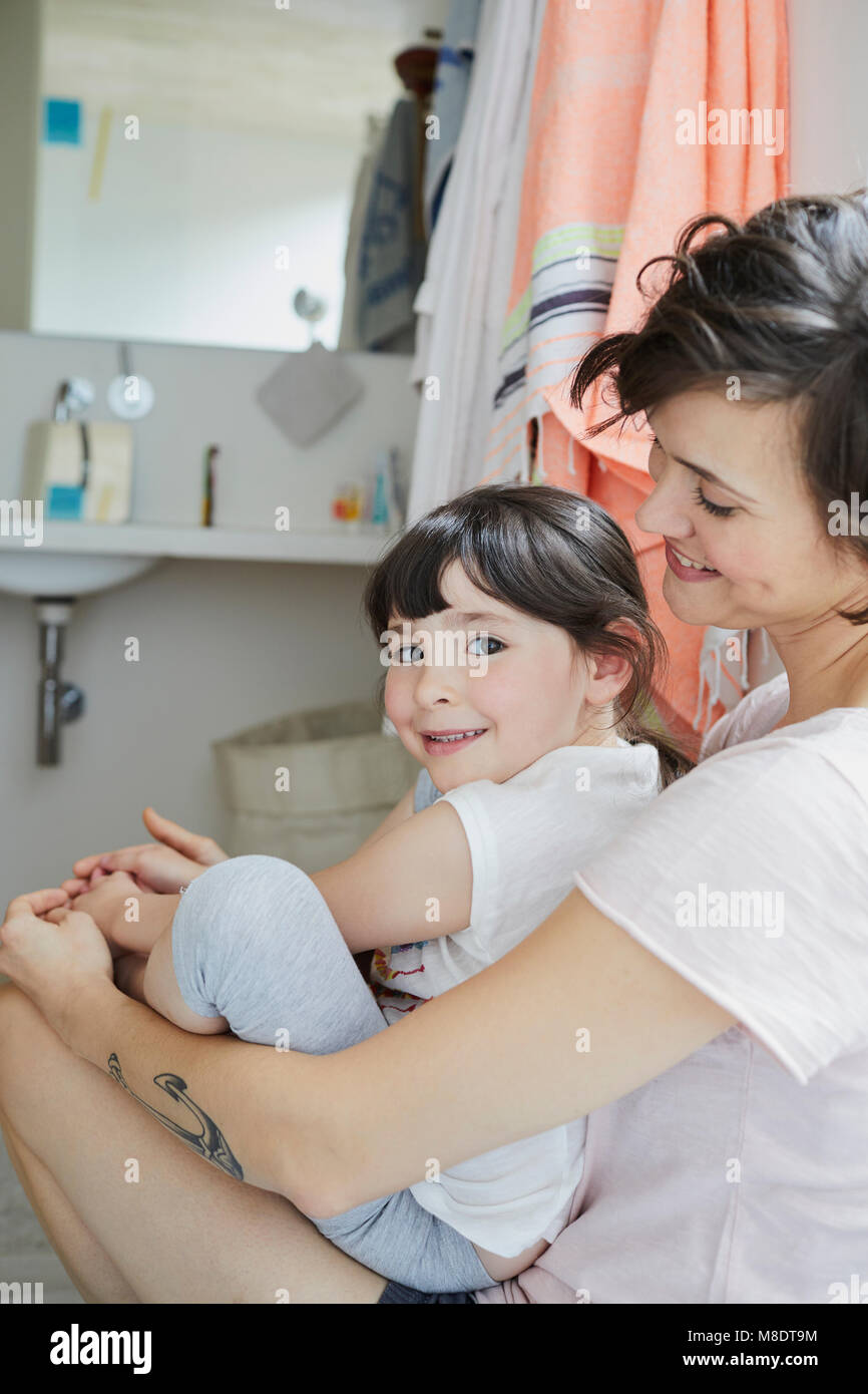 Mutter und Tochter sitzen zusammen im Bad, lächelnd Stockfoto