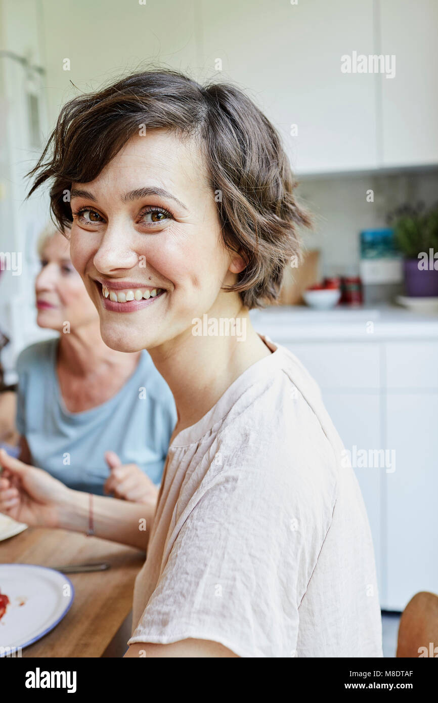 Portrait von Mitte der erwachsenen Frau am Tisch, lächelnd Stockfoto