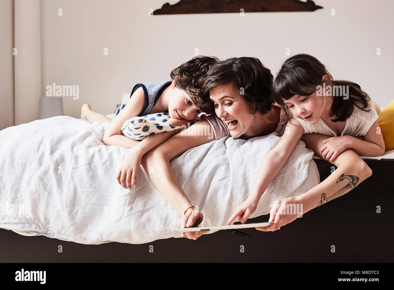 Mutter, Sohn und Tochter auf dem Bett liegend, mit digitalen Tablet Stockfoto