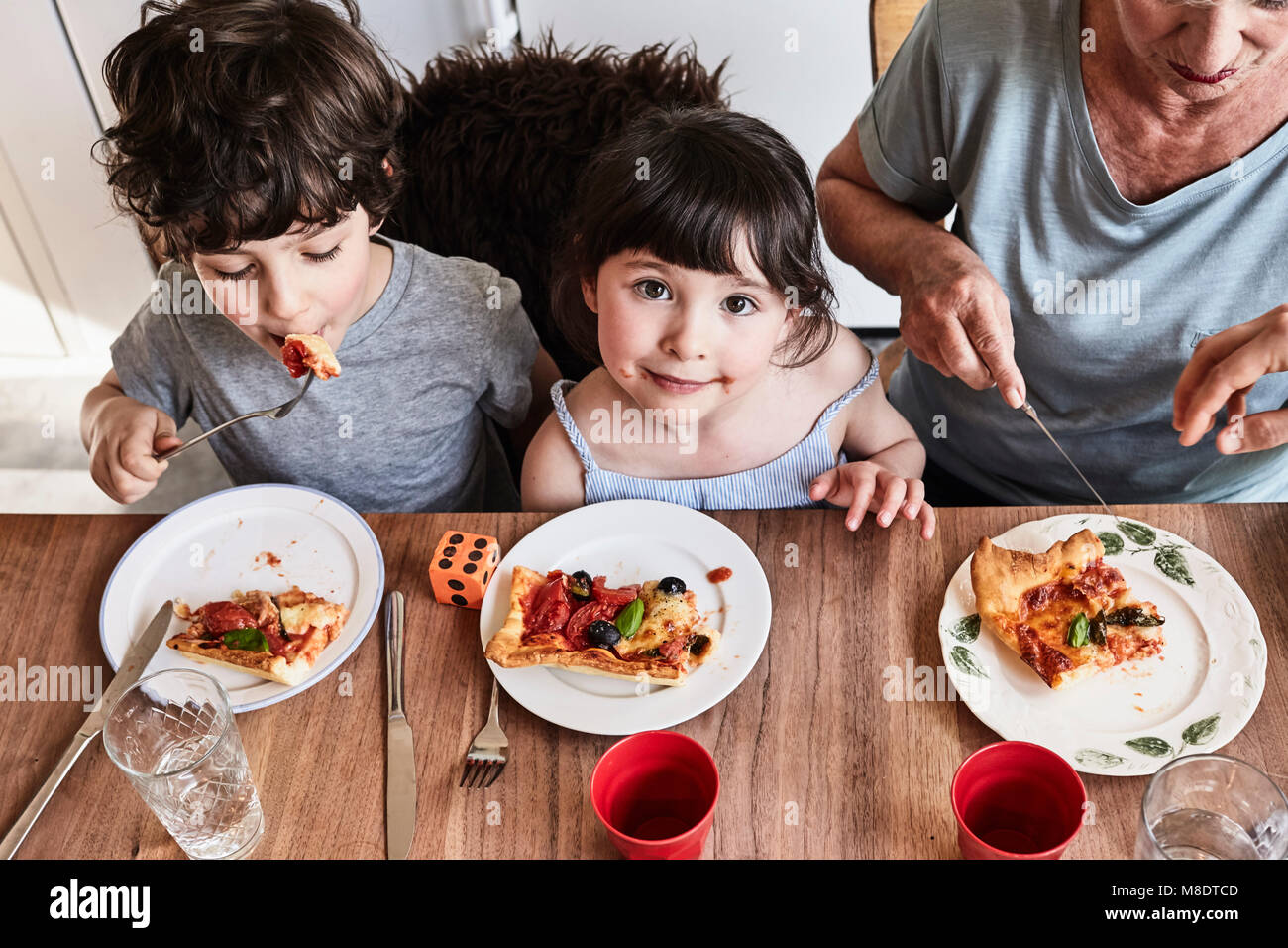 Großmutter an den Küchentisch sitzen mit Enkelkindern, essen Pizza, Erhöhte Ansicht Stockfoto