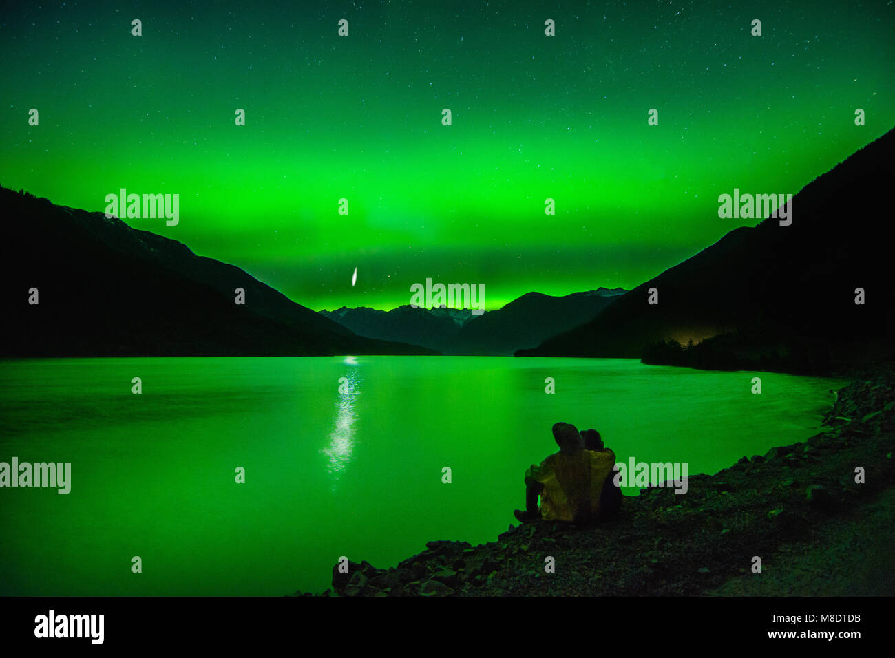 Paar sitzen neben Lillooet Lake, Northern Lights, Pemberton, British Columbia, Kanada Stockfoto