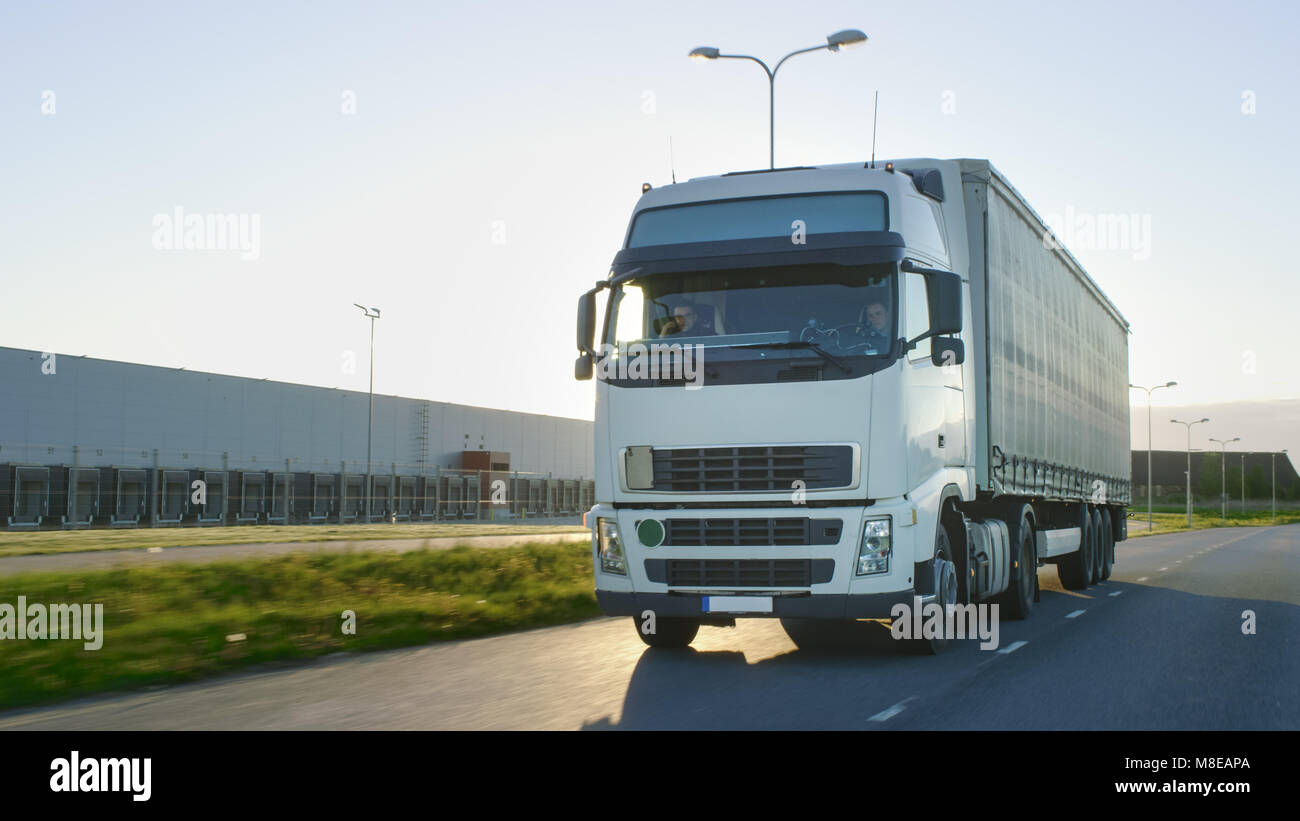 Semi Truck mit Cargo Trailer Bewegen auf einer Autobahn. Weisse Truck fährt durch industrielle Lagerbereich. Stockfoto