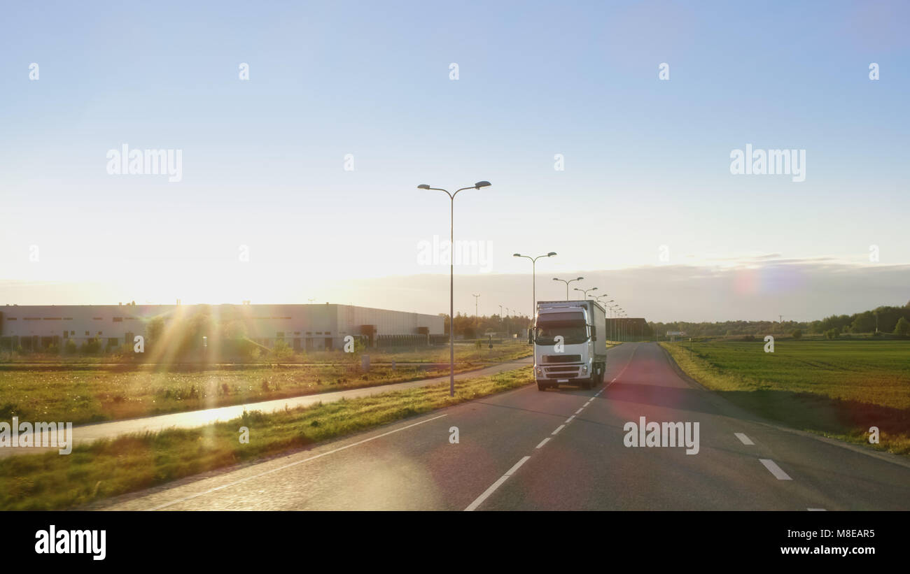 Weiß Semi Truck mit Cargo Anhänger fährt auf einer Autobahn mit schönen sonnigen Landschaft im Hintergrund. Stockfoto