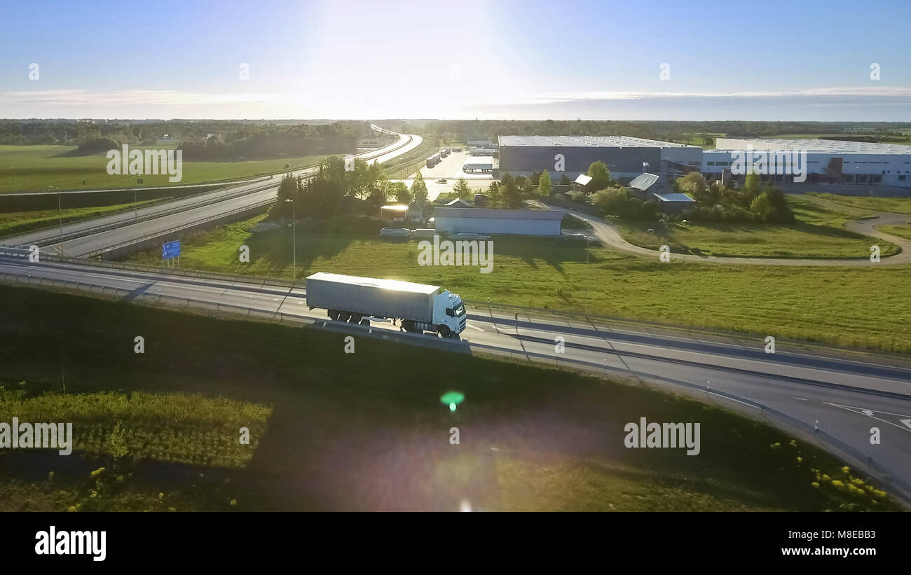 Luftbild des Weißen Semi Truck mit Cargo Trailer vorbei Autobahnbrücke/Brücke. 18 Wheeler ist neu, laden Lager sind zu sehen im Hinterg Stockfoto