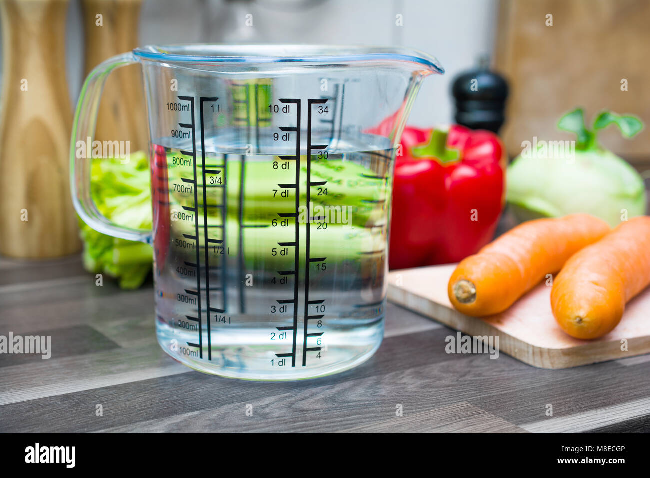 800ml/8 dl Wasser In einem Messbecher auf eine Arbeitsplatte in der Küche mit Gemüse Stockfoto