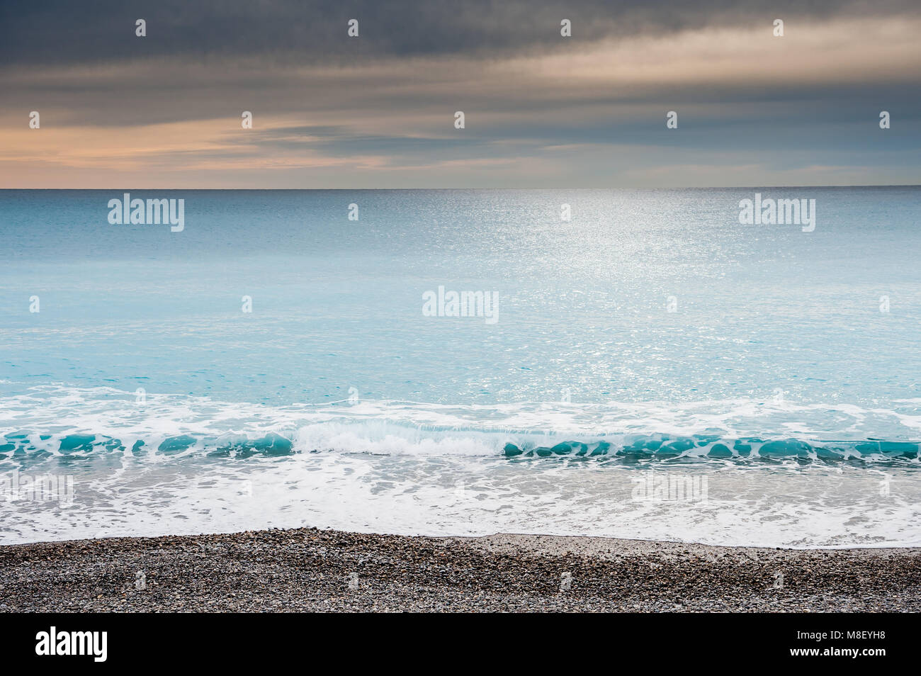 Ein Blick auf das Ligurische Meer von der Promenade in Nizza im Süden Frankreichs. Im Winter mit einem dramatischen Himmel genommen und relativ ruhigem Wasser. Stockfoto