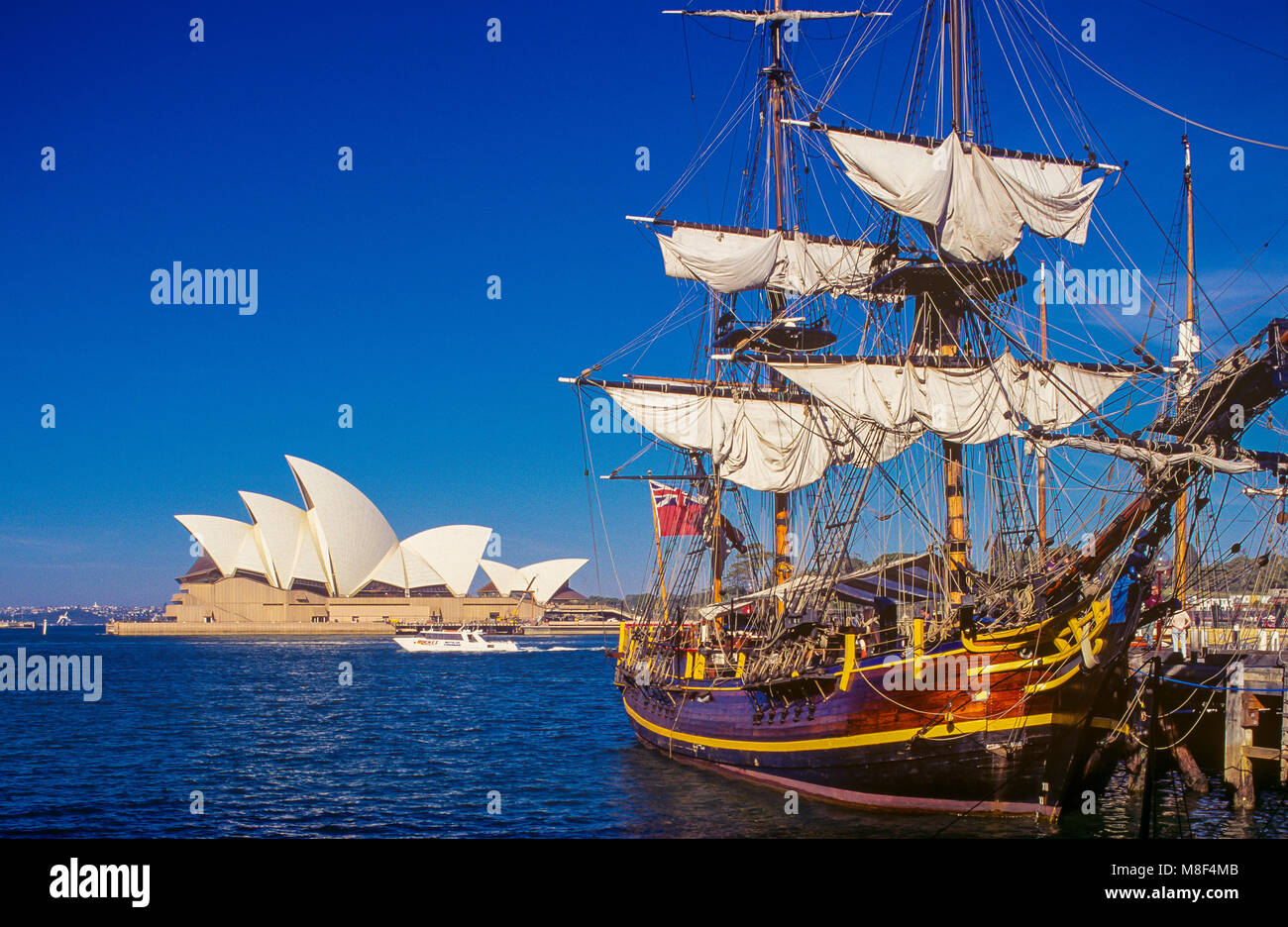 Die HMS Bounty replik Schiff vertäut an der Campbell's Cove Pier im Hafen von Sydney in Sydney, Australien. Die berühmte Oper von Sydney kann im Hintergrund gesehen werden. Stockfoto