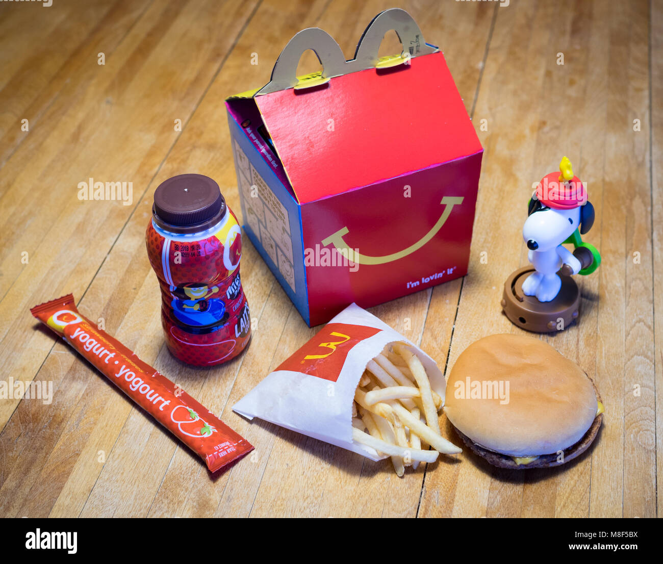 Ein McDonald's Happy Meal mit einem Cheeseburger, Pommes frites, Schokolade, Milch, Joghurt, und Snoopy Spielzeug. Stockfoto
