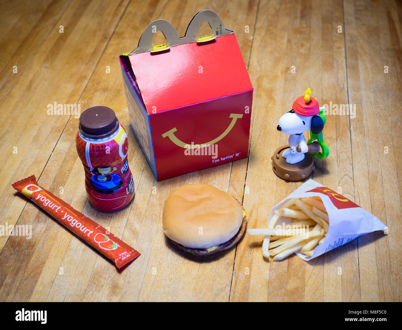 Ein McDonald's Happy Meal mit einem Cheeseburger, Pommes frites, Schokolade, Milch, Joghurt, und Snoopy Spielzeug. Stockfoto