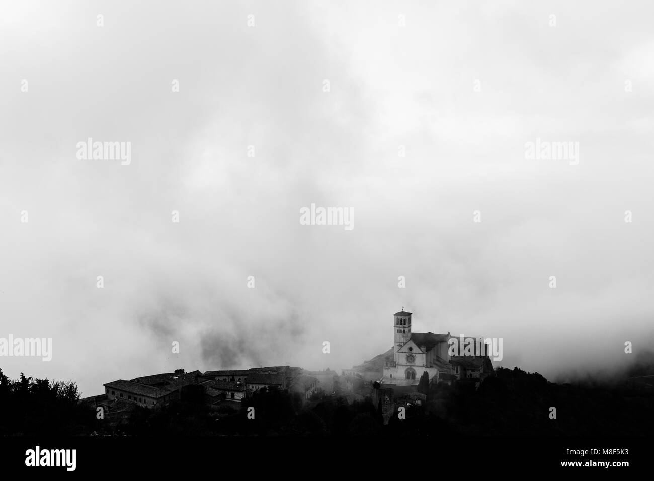 Blick auf die St. Francis päpstliche Kirche in Assisi (Umbrien, Italien) in der Mitte der Aufhebung Morgennebel Stockfoto