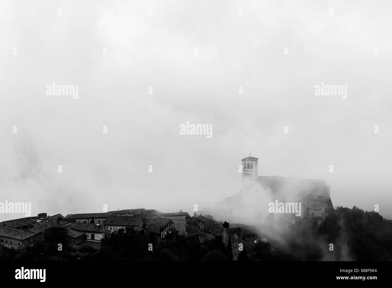 Blick auf die St. Francis päpstliche Kirche in Assisi (Umbrien, Italien) in der Mitte der Aufhebung Morgennebel Stockfoto