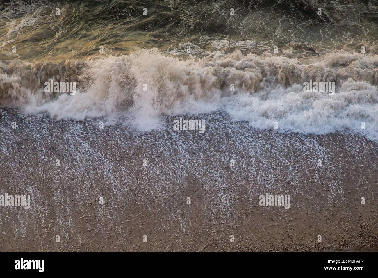 Ein Luftbild von Surf Wellen an einem Kieselstrand in der Abendsonne Stockfoto