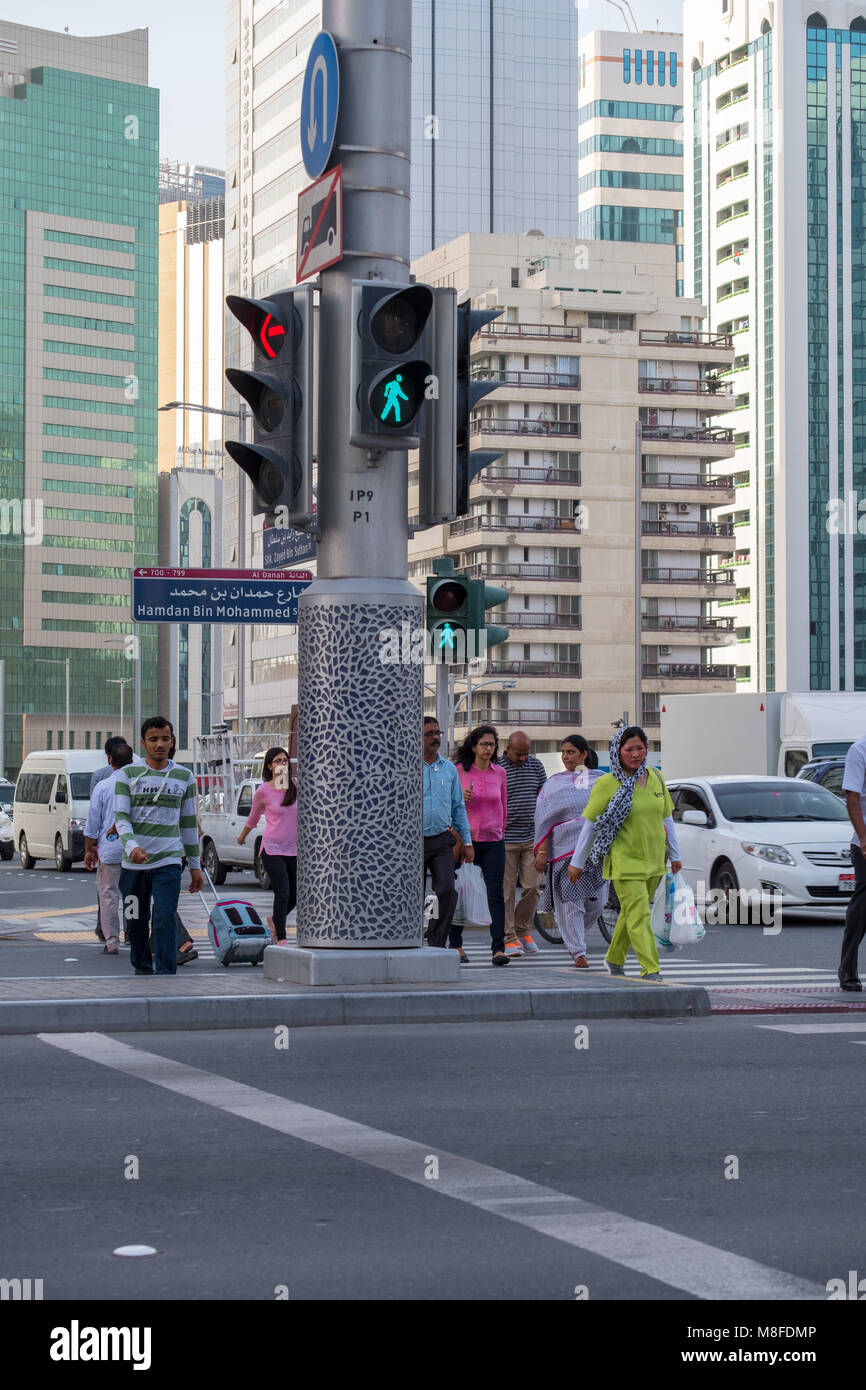 Menschen, die über die Straße auf die grüne Ampel in Abu Dhabi VAE. Stockfoto