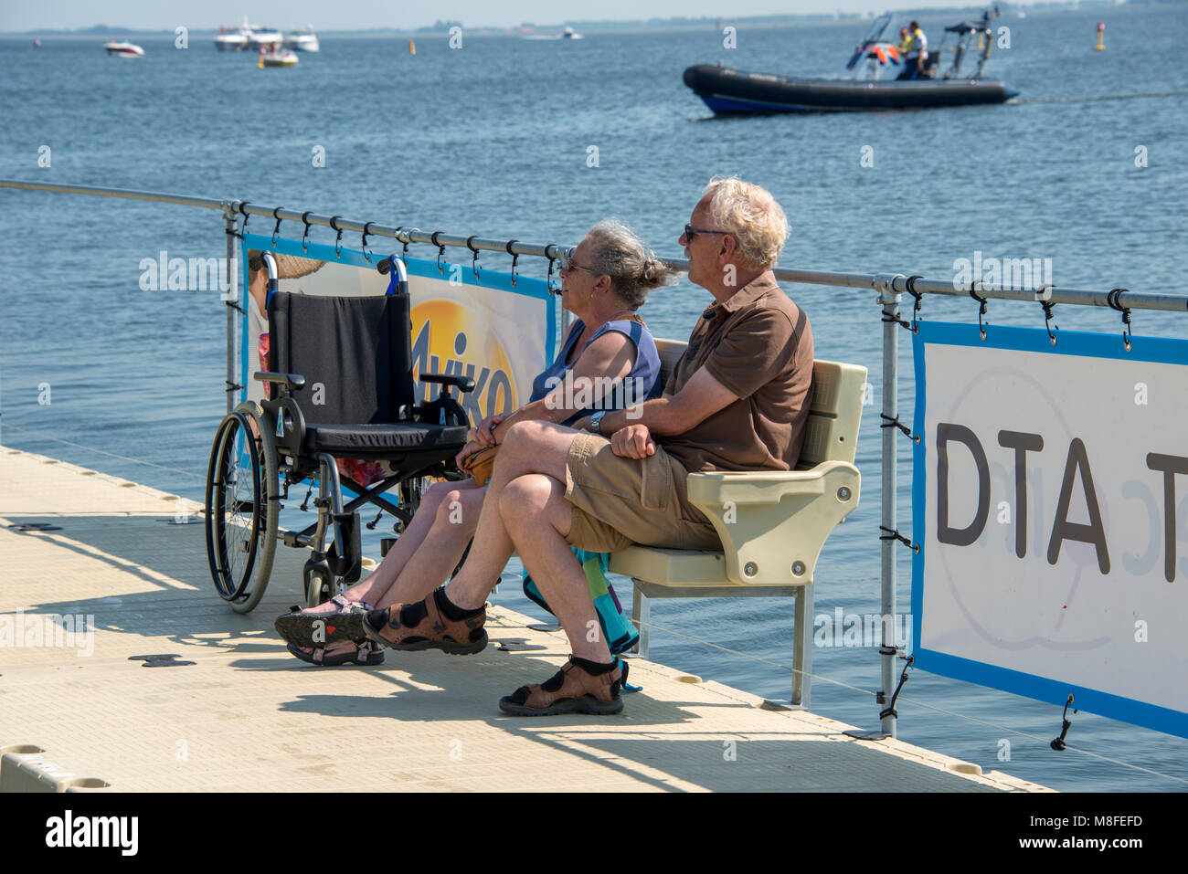 Hellevoetlsuis, Holland, 08.07.2013: Ältere Paar sitzen und mit einem Rollstuhl Wasserlinie entspannen, dieses Wasser ist das Haringvliet, wo viele waterspo Stockfoto