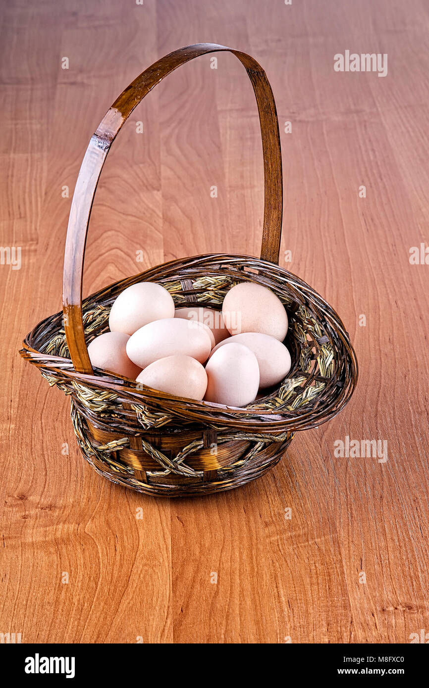 Eiern in einem Korb auf einem hölzernen Hintergrund Stockfoto