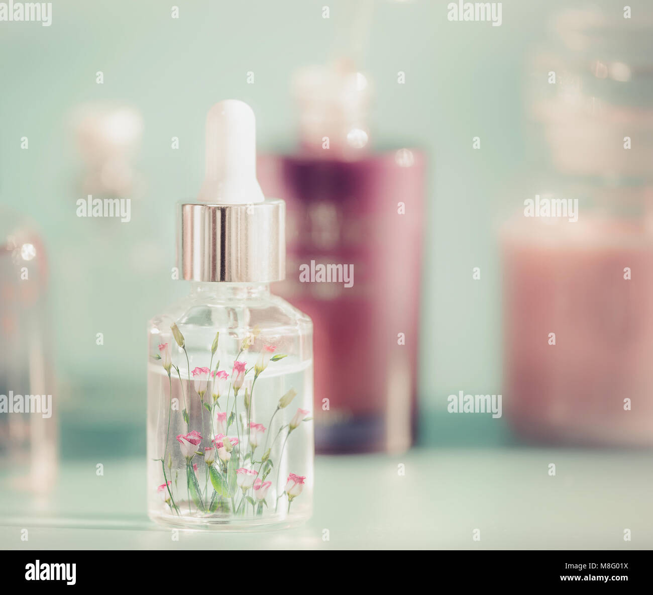 Transparente kosmetische Flasche mit flüssigem, Pipette und kleinen rosa Blüten. Floral essence oder pflanzliche Serum auf Tabelle extract, Vorderansicht. Schönheit und Mode Stockfoto