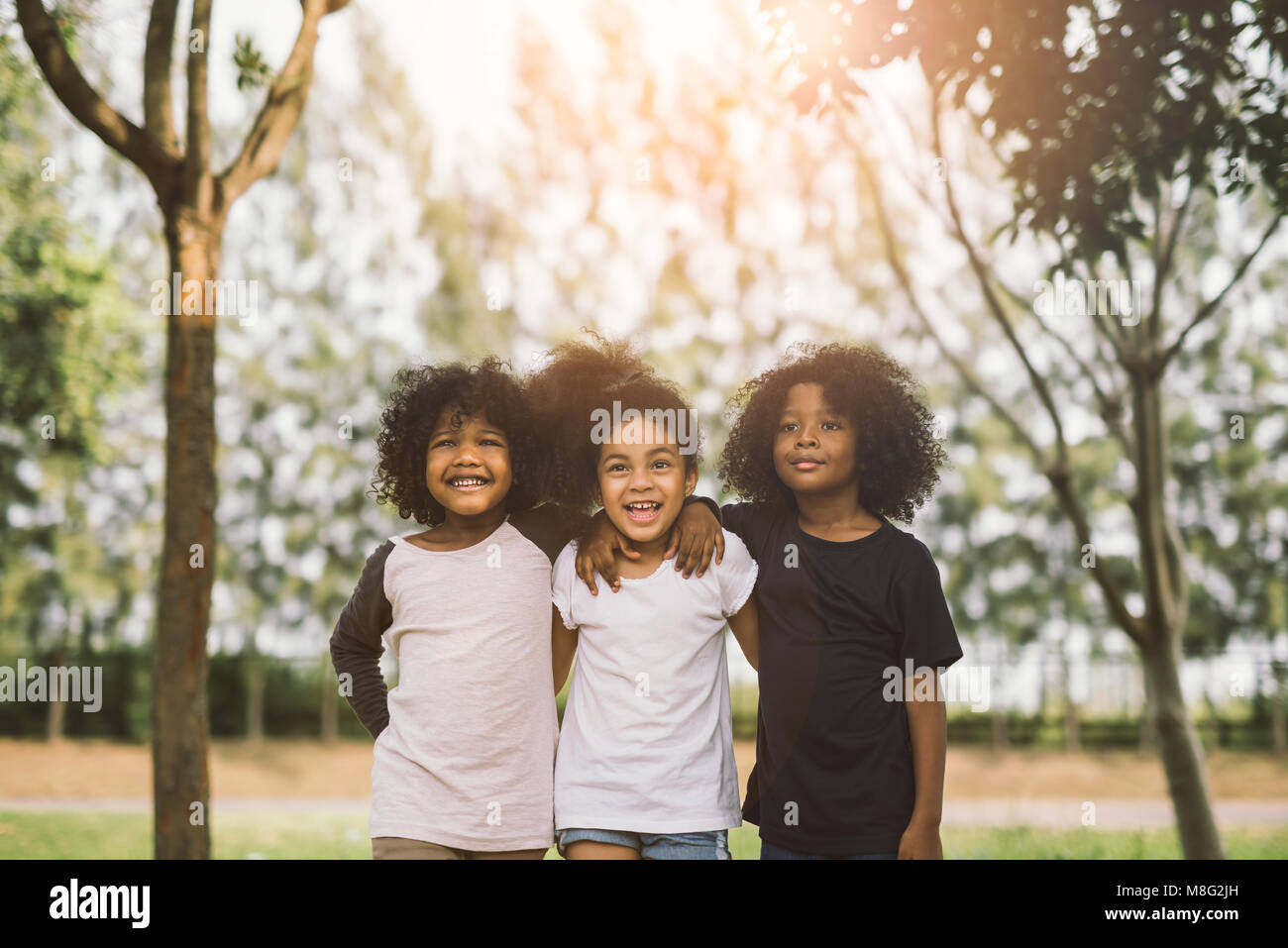 Kinder Freundschaft miteinander Lächeln Glück Konzept. Cute afrikanische amerikanische kleine Jungen und Mädchen umarmen sich im Sommer sonnigen Tag Stockfoto