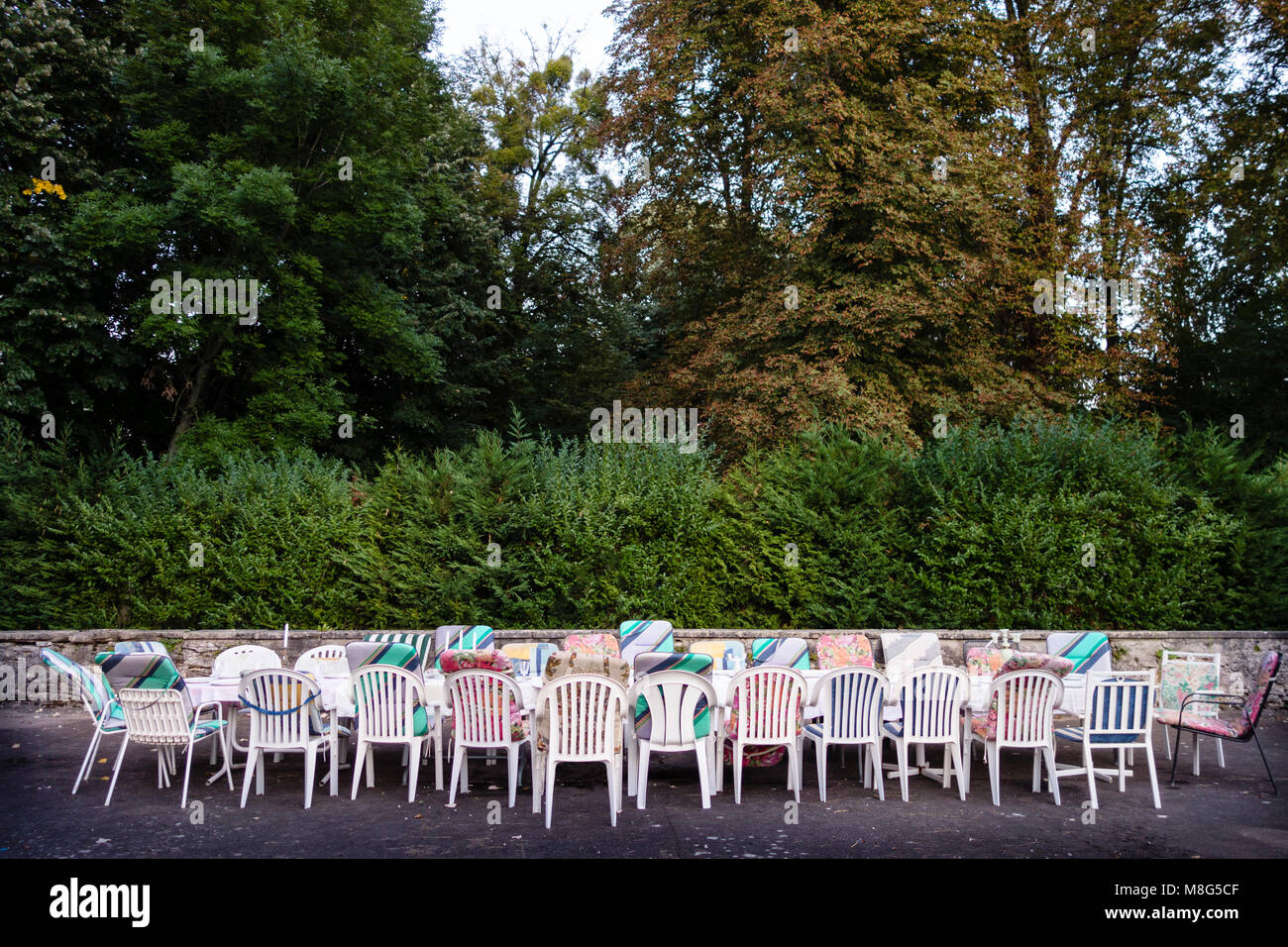 Langer Tisch und Stühle mit gemischten Polsterung draußen im Innenhof warten auf eine Gruppe von Freunden auf Urlaub, sie zu laden. Konzept für Team Building, Freundschaft und Zusammengehörigkeit. Stockfoto