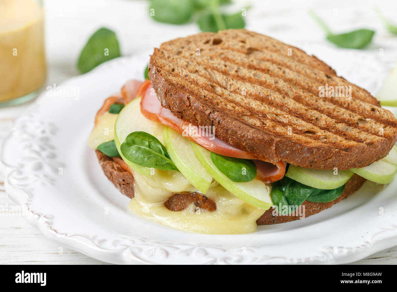 Sandwich mit Schinken, Käse Brie oder Camembert, Spinat, Apple und Senf. Gourmet Frühstück Nahaufnahme. Selektiver Fokus Stockfoto