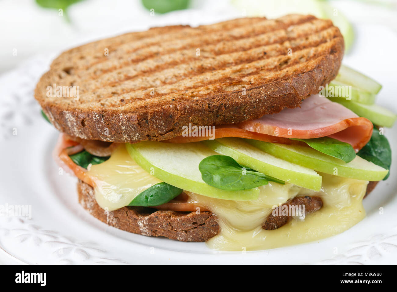 Sandwich mit Schinken, Käse Brie oder Camembert, Spinat, Apple und Senf. Gourmet Frühstück Nahaufnahme. Selektiver Fokus Stockfoto
