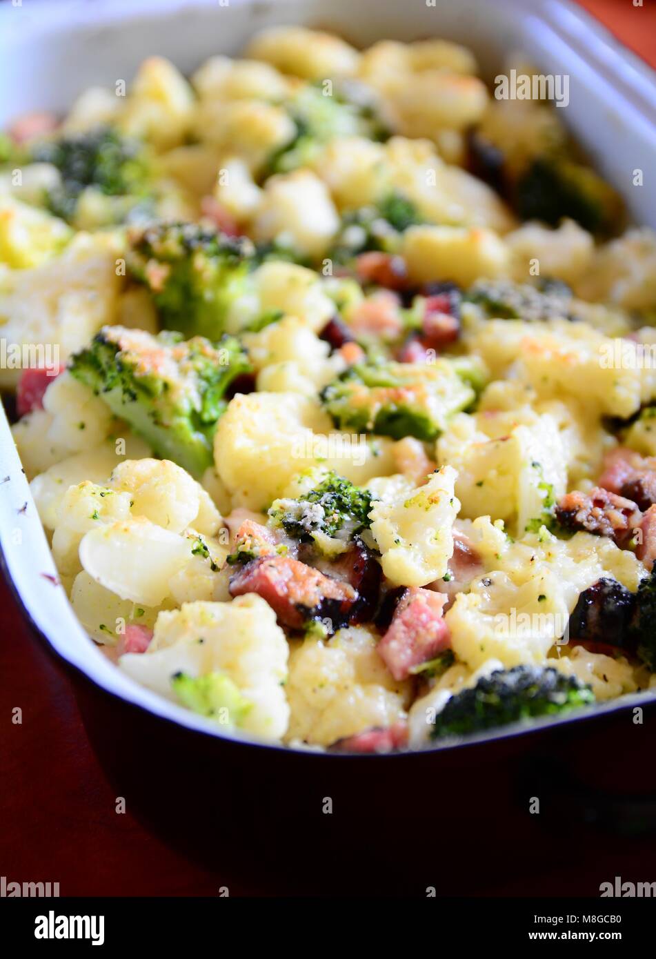 Gebackener Blumenkohl und Brokkoli mit geriebenem Parmesan und Speck in Schwarz Pan. Stockfoto