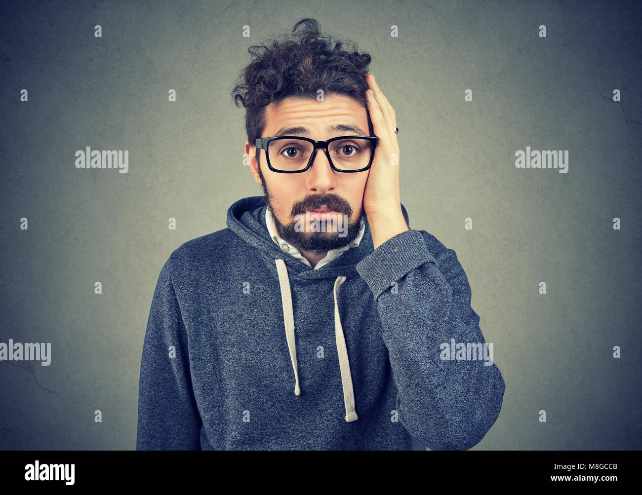 Portrait von enttäuscht betonte bärtiger junger Mann auf einem grauen Hintergrund. Negative menschliche Emotionen Stockfoto