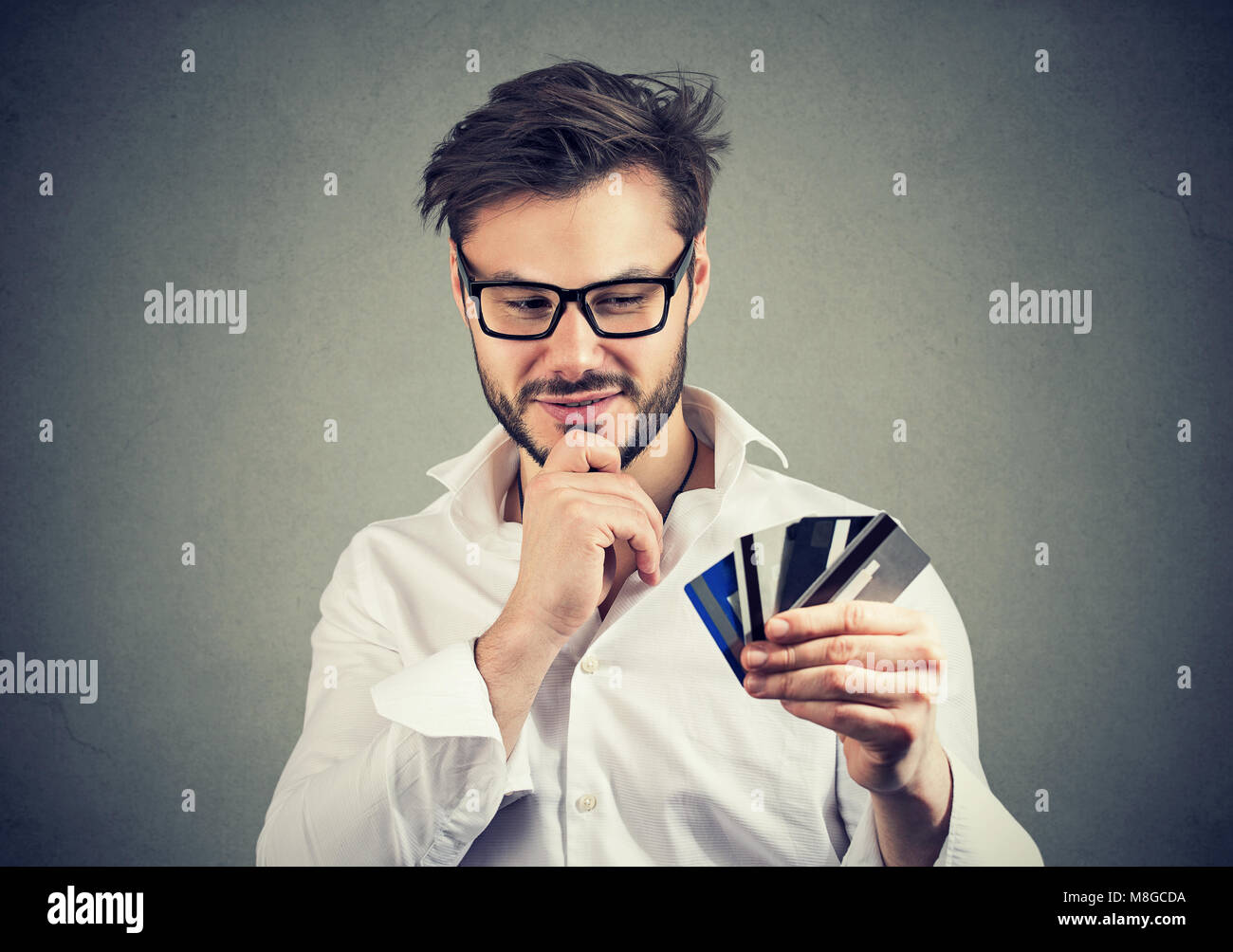 Jungen gutaussehenden Mann in Gläser, die Wahl der Kreditkarten mit der finanziellen Stabilität begeistert. Stockfoto