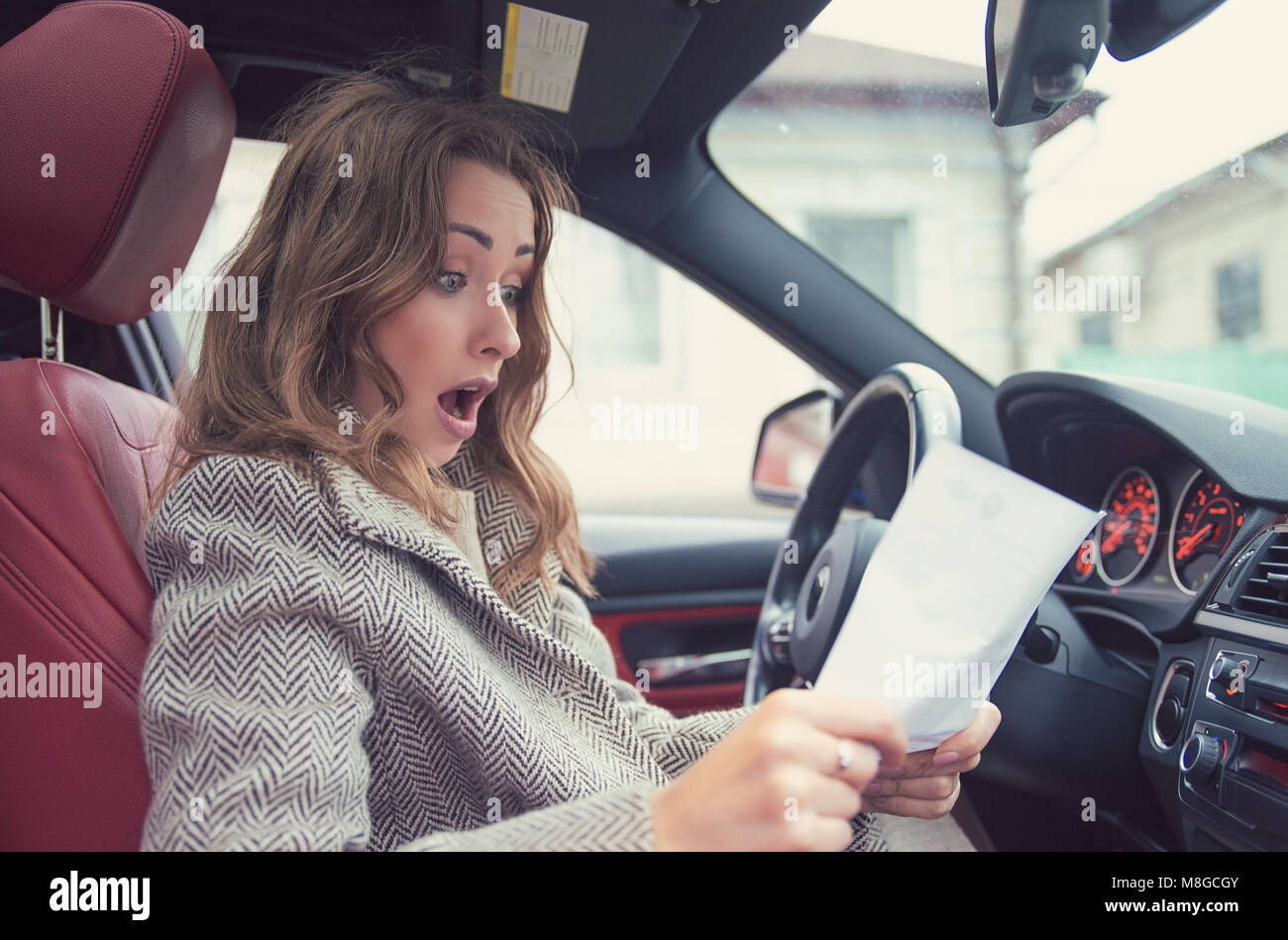 Junge Mädchen in einem Auto sitzen und lesen feine Papiere, schauen, frustriert. Stockfoto