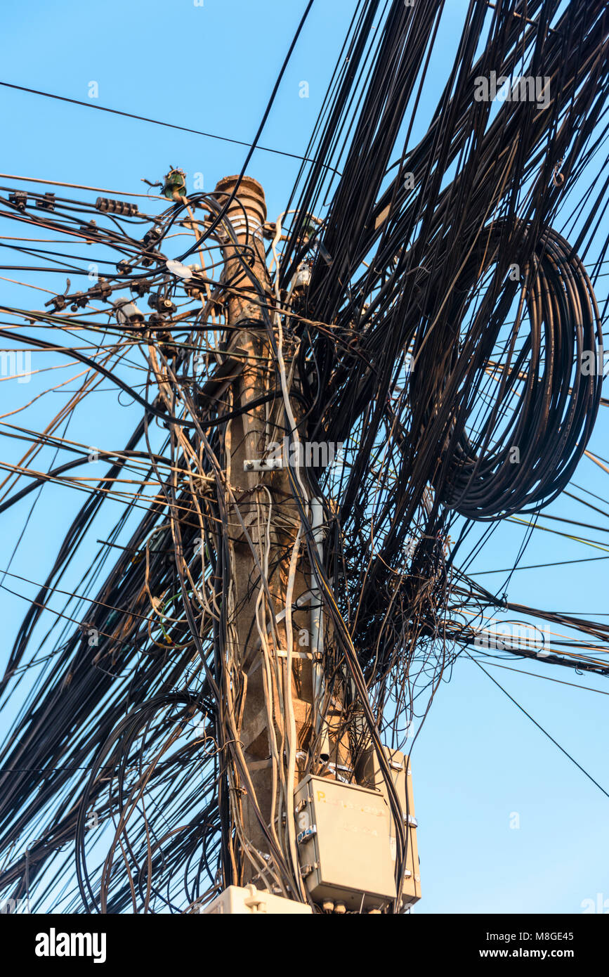 Strommast mit Dutzenden von gefährlichen ungepflegt unordentlich Kabel und Leitungen Stockfoto