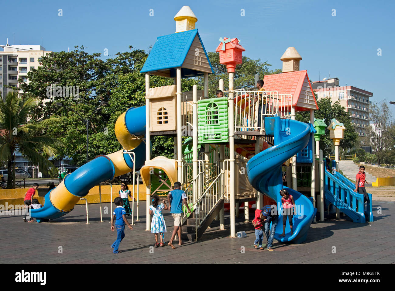 Kinder spielen auf dem Spielplatz des Viharamahadevi Park (Vihara maha Devi) an einem sonnigen Tag mit blauen Himmel. Stockfoto