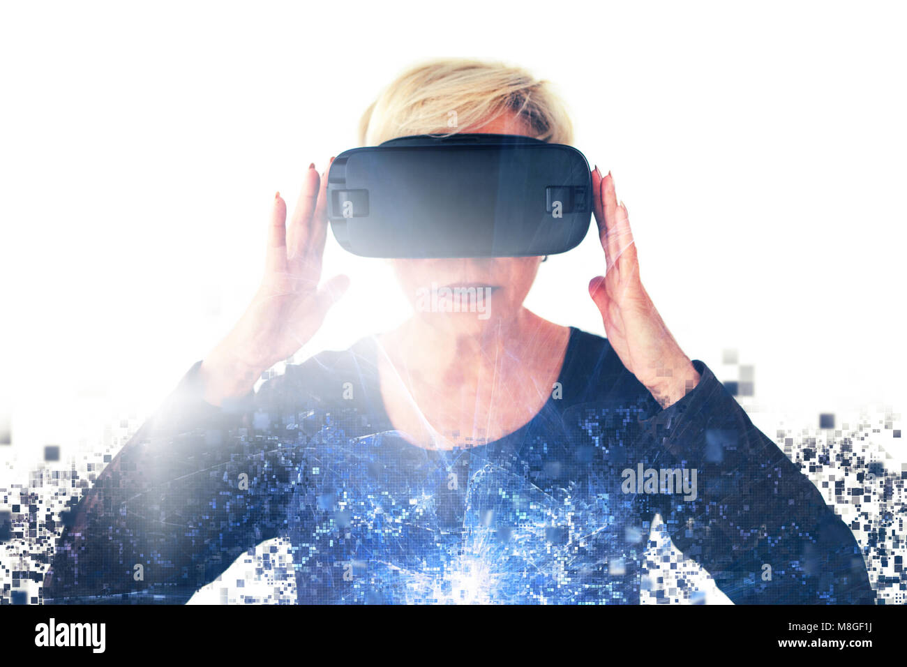 Eine ältere Frau in virtual reality Brillen ist durch Pixel verteilt. Konzeptionelle Fotografie mit visuellen Effekten mit einer älteren Person mit moderner Technologie. Stockfoto