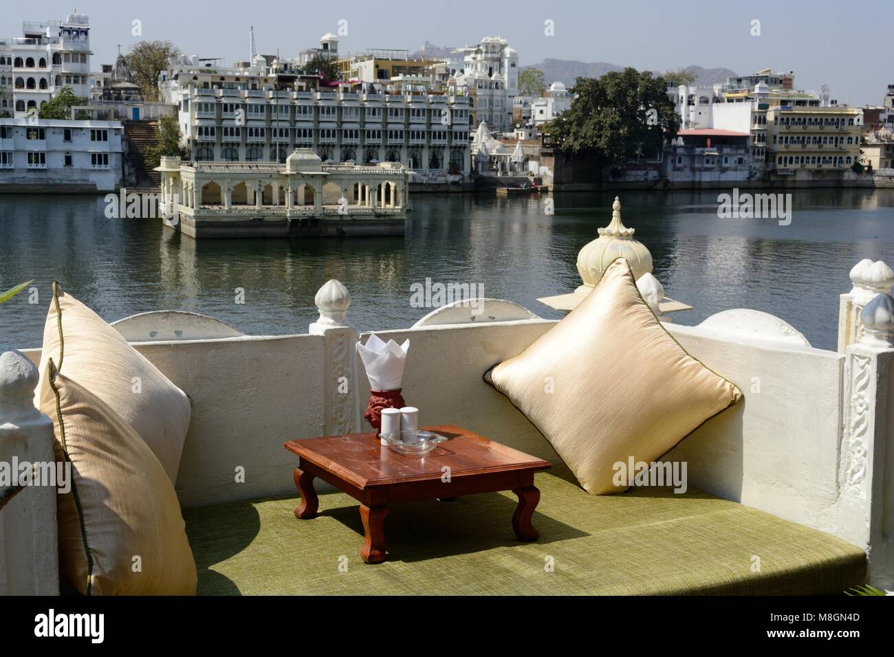 Niedrige Sitzecke mit Kissen und Tisch in einem Restaurant mit Blick auf den See Pichola Udaipur Rajashan Indien Stockfoto