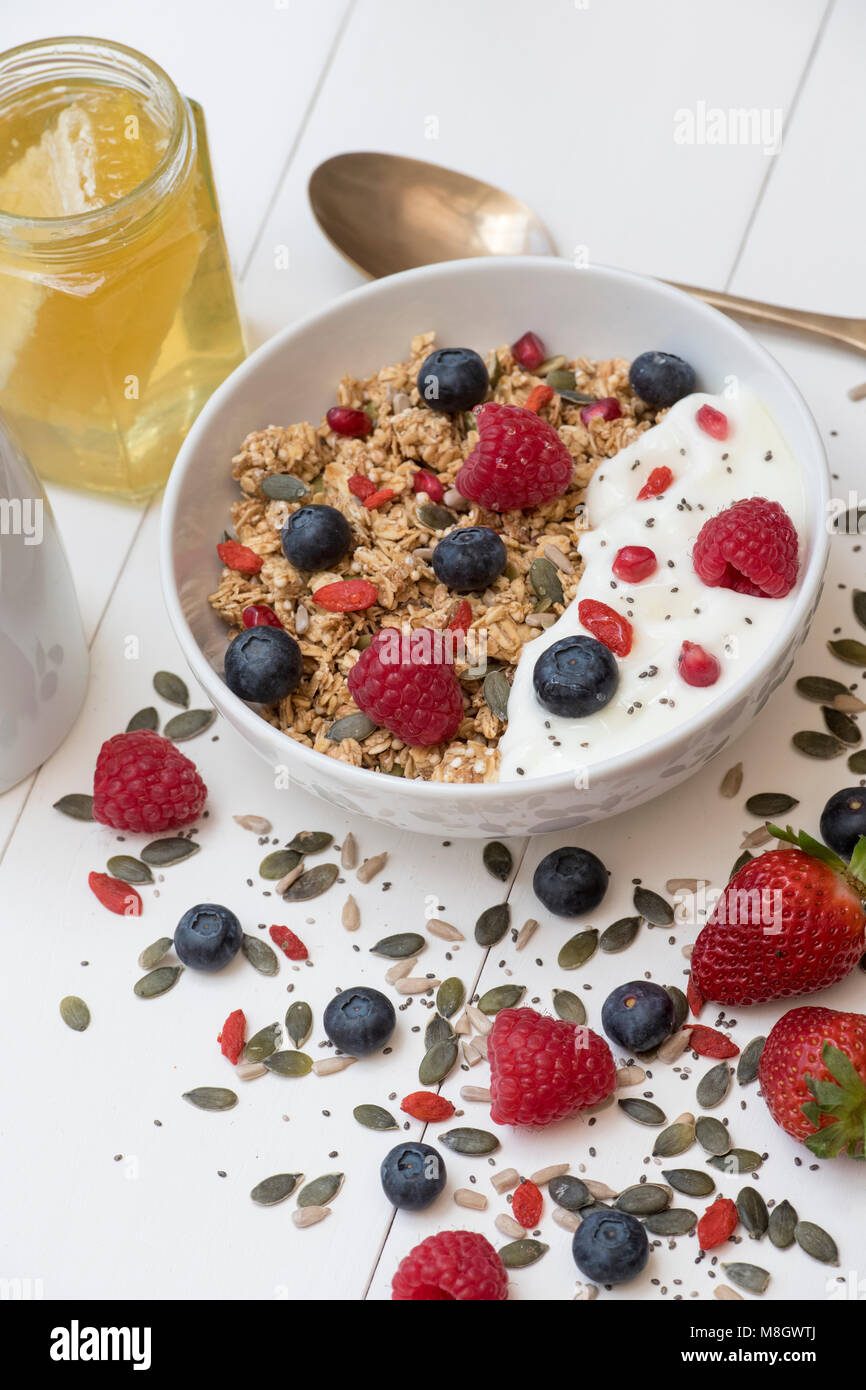 Frühstück Schüssel Müsli, Früchte, Samen, Joghurt und Honig auf einem weißen Holz Hintergrund Stockfoto