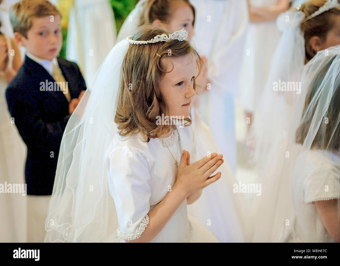 Katholischen jungen und Mädchen, die das Sakrament der ersten Heiligen Kommunion empfangen. Stockfoto