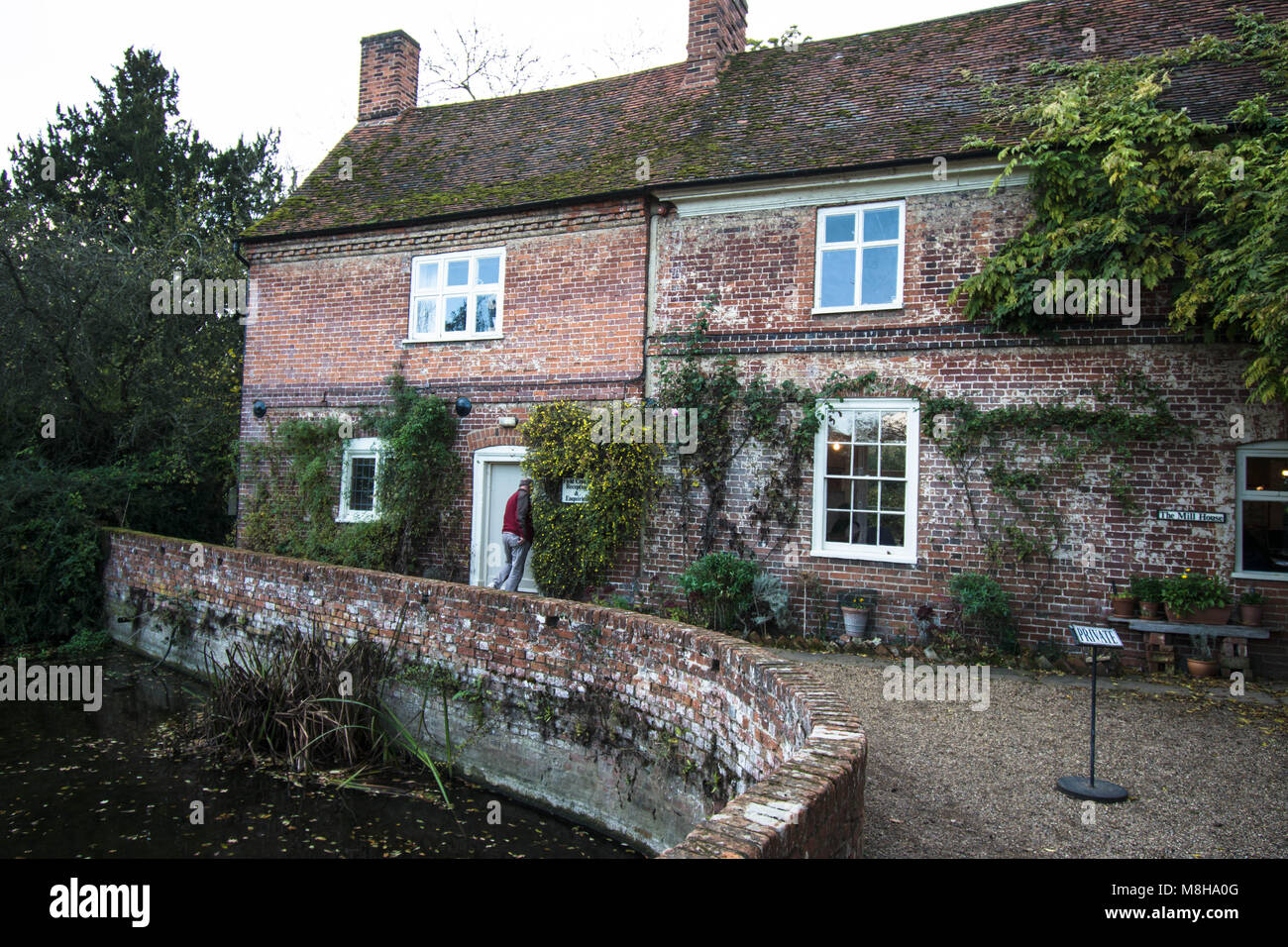 Flatford Mill Constable Country Landschaft Mauerbrücke Steinhaus Häuser Wasserteich Besucher besuchen Ziegelsteine Kies Fenster Fenster Stockfoto