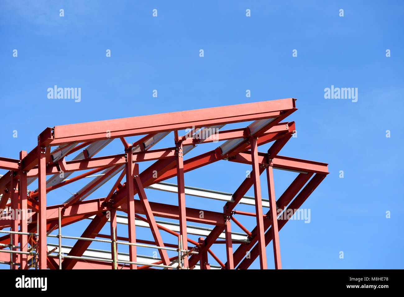 Bauarbeiten sind im Gange. Roter Grundierung lackiertes Stahlwerk. Gerollte Stahlträger rsj-Rahmen. Blauer Himmel Stockfoto